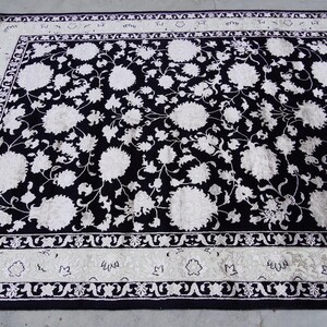 A 5.5x7.9 ft hand-knotted rug featuring a large, ornate ivory and blue central medallion on a deep navy blue field. The field is filled with intricate scrolling vines and small floral motifs. A wide, multi-layered border in ivory and light blue frames the rug. The rug is made of wool with silk highlights that give it a subtle sheen, finished with a short white fringe at the top and bottom.
