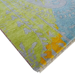 Hand-knotted wool Oushak rug in paisley pattern; rolled samples in teal, blue, orange for a textured floor decor rug.