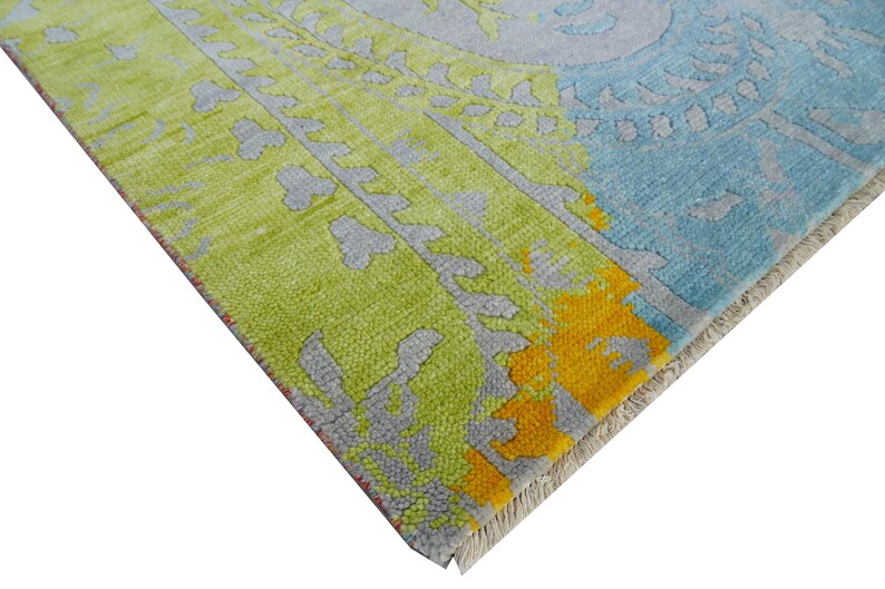 Hand-knotted wool Oushak rug in paisley pattern; rolled samples in teal, blue, orange for a textured floor decor rug.