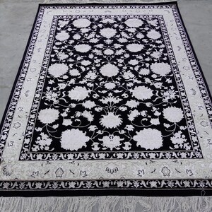 A 5.5x7.9 ft hand-knotted rug featuring a large, ornate ivory and blue central medallion on a deep navy blue field. The field is filled with intricate scrolling vines and small floral motifs. A wide, multi-layered border in ivory and light blue frames the rug. The rug is made of wool with silk highlights that give it a subtle sheen, finished with a short white fringe at the top and bottom.