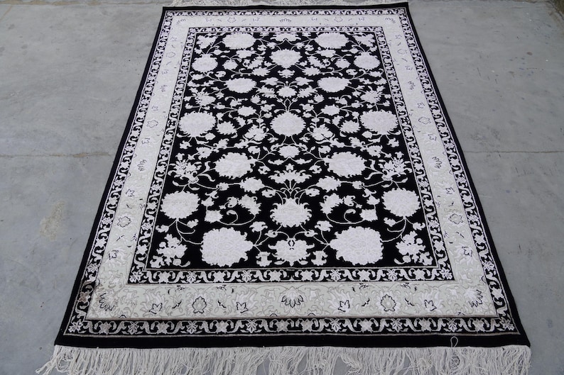 A 5.5x7.9 ft hand-knotted rug featuring a large, ornate ivory and blue central medallion on a deep navy blue field. The field is filled with intricate scrolling vines and small floral motifs. A wide, multi-layered border in ivory and light blue frames the rug. The rug is made of wool with silk highlights that give it a subtle sheen, finished with a short white fringe at the top and bottom.