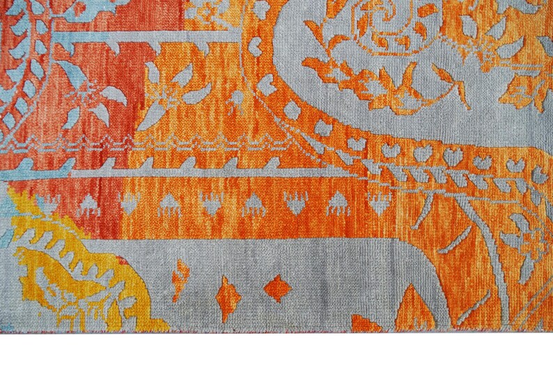 Hand-knotted wool Oushak rug in paisley pattern; rolled samples in teal, blue, orange for a textured floor decor rug.