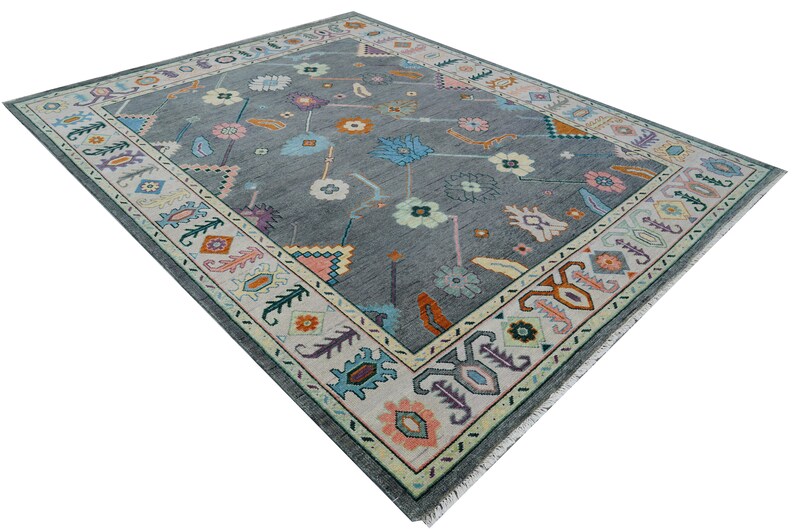 Hand-knotted wool rug in floral Turkish Oushak style, 8x10; blue-gray field with teal, rust, and peach blossoms.