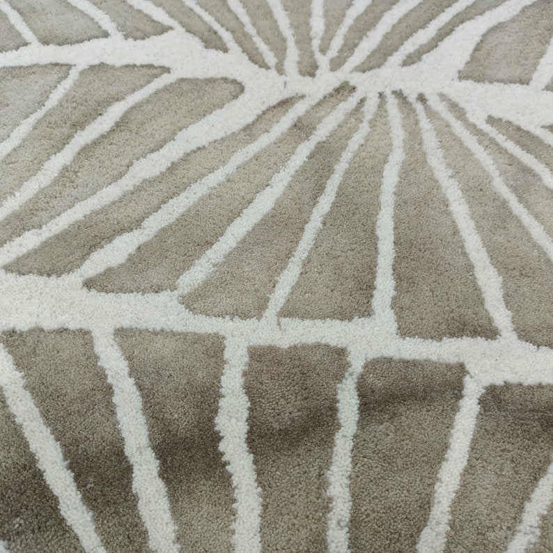 Round hand-tufted wool rug with a vibrant floral pattern in pink, red, orange, and white on a pale background; textured modern living room rug.