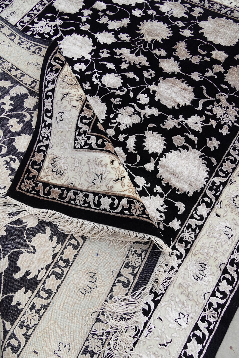 A 5.5x7.9 ft hand-knotted rug featuring a large, ornate ivory and blue central medallion on a deep navy blue field. The field is filled with intricate scrolling vines and small floral motifs. A wide, multi-layered border in ivory and light blue frames the rug. The rug is made of wool with silk highlights that give it a subtle sheen, finished with a short white fringe at the top and bottom.