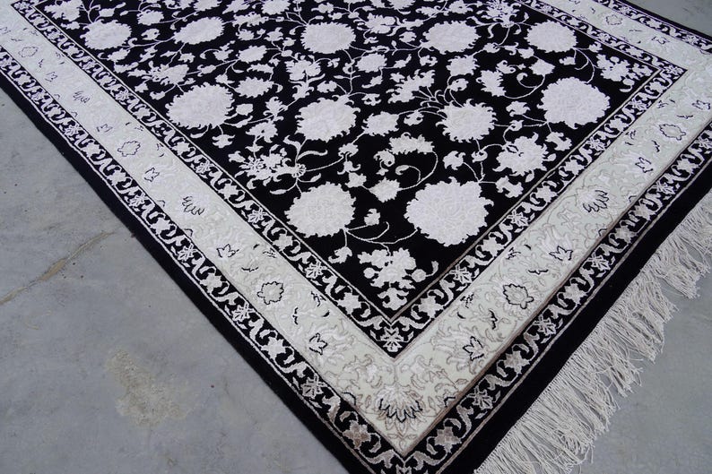 A 5.5x7.9 ft hand-knotted rug featuring a large, ornate ivory and blue central medallion on a deep navy blue field. The field is filled with intricate scrolling vines and small floral motifs. A wide, multi-layered border in ivory and light blue frames the rug. The rug is made of wool with silk highlights that give it a subtle sheen, finished with a short white fringe at the top and bottom.