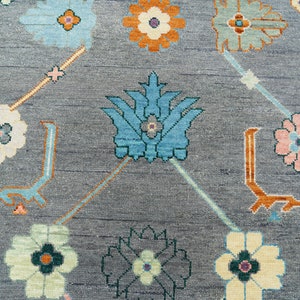 Hand-knotted wool rug in floral Turkish Oushak style, 8x10; blue-gray field with teal, rust, and peach blossoms.