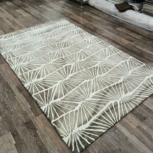 Round hand-tufted wool rug with a vibrant floral pattern in pink, red, orange, and white on a pale background; textured modern living room rug.