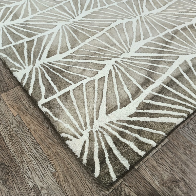 Round hand-tufted wool rug with a vibrant floral pattern in pink, red, orange, and white on a pale background; textured modern living room rug.