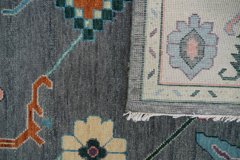 Hand-knotted wool rug in floral Turkish Oushak style, 8x10; blue-gray field with teal, rust, and peach blossoms.