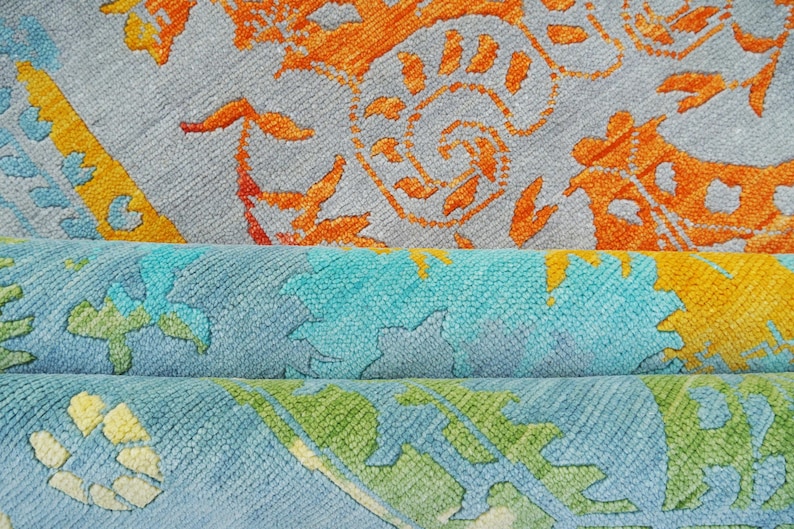 Hand-knotted wool Oushak rug in paisley pattern; rolled samples in teal, blue, orange for a textured floor decor rug.