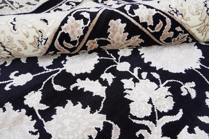 A 5.5x7.9 ft hand-knotted rug featuring a large, ornate ivory and blue central medallion on a deep navy blue field. The field is filled with intricate scrolling vines and small floral motifs. A wide, multi-layered border in ivory and light blue frames the rug. The rug is made of wool with silk highlights that give it a subtle sheen, finished with a short white fringe at the top and bottom.