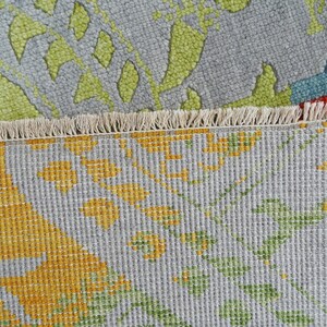 Hand-knotted wool Oushak rug in paisley pattern; rolled samples in teal, blue, orange for a textured floor decor rug.