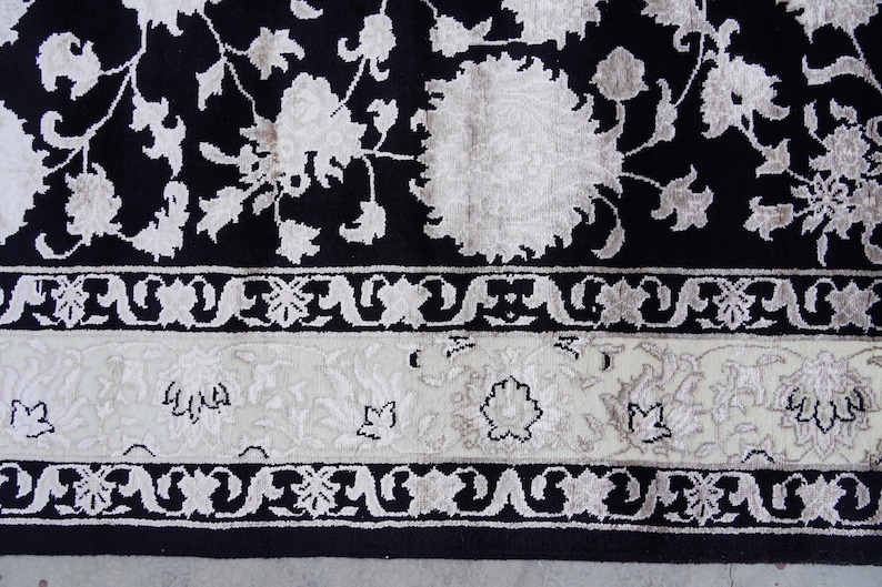 A 5.5x7.9 ft hand-knotted rug featuring a large, ornate ivory and blue central medallion on a deep navy blue field. The field is filled with intricate scrolling vines and small floral motifs. A wide, multi-layered border in ivory and light blue frames the rug. The rug is made of wool with silk highlights that give it a subtle sheen, finished with a short white fringe at the top and bottom.