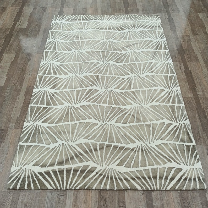 Round hand-tufted wool rug with a vibrant floral pattern in pink, red, orange, and white on a pale background; textured modern living room rug.