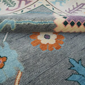 Hand-knotted wool rug in floral Turkish Oushak style, 8x10; blue-gray field with teal, rust, and peach blossoms.