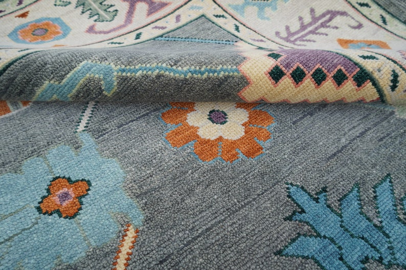 Hand-knotted wool rug in floral Turkish Oushak style, 8x10; blue-gray field with teal, rust, and peach blossoms.