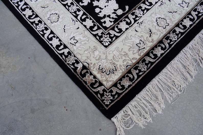 A 5.5x7.9 ft hand-knotted rug featuring a large, ornate ivory and blue central medallion on a deep navy blue field. The field is filled with intricate scrolling vines and small floral motifs. A wide, multi-layered border in ivory and light blue frames the rug. The rug is made of wool with silk highlights that give it a subtle sheen, finished with a short white fringe at the top and bottom.