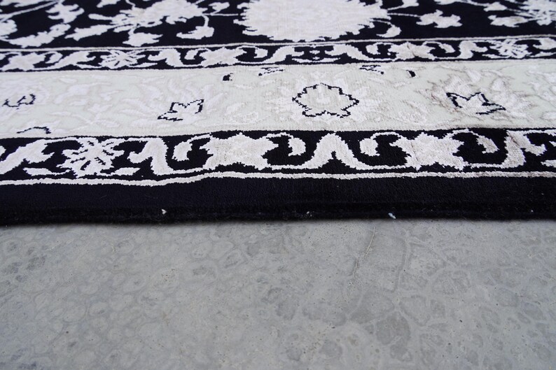 A 5.5x7.9 ft hand-knotted rug featuring a large, ornate ivory and blue central medallion on a deep navy blue field. The field is filled with intricate scrolling vines and small floral motifs. A wide, multi-layered border in ivory and light blue frames the rug. The rug is made of wool with silk highlights that give it a subtle sheen, finished with a short white fringe at the top and bottom.