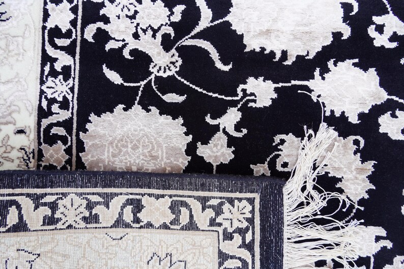 A 5.5x7.9 ft hand-knotted rug featuring a large, ornate ivory and blue central medallion on a deep navy blue field. The field is filled with intricate scrolling vines and small floral motifs. A wide, multi-layered border in ivory and light blue frames the rug. The rug is made of wool with silk highlights that give it a subtle sheen, finished with a short white fringe at the top and bottom.