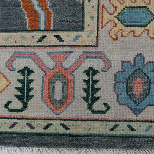Hand-knotted wool rug in floral Turkish Oushak style, 8x10; blue-gray field with teal, rust, and peach blossoms.