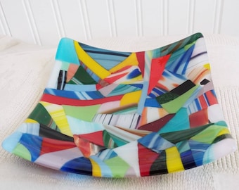 May include: A colorful glass dish with a mosaic design. The dish is made of many small pieces of glass in various colors, including red, yellow, blue, green, and white.