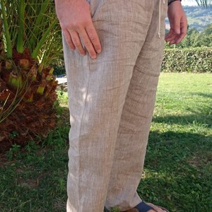 Puede incluir: Pantalones de lino color beige con cintura con cord&oacute;n y bolsillos laterales. Los pantalones son de color neutro y parecen ligeros. La persona lleva sandalias. Adecuados para uso casual.