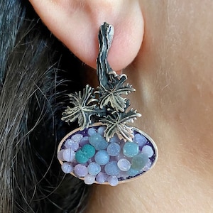 May include: Silver earrings featuring a cluster of purple and green beads, a silver branch with leaves, and the text "ArMat Silver".
