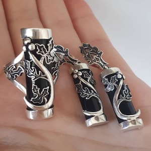May include: A silver ring and earrings set with black onyx stones and intricate floral designs.