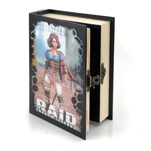Può includere: Una scatola di legno nera e marrone con un coperchio incernierato. La parte anteriore della scatola presenta un'illustrazione colorata di una donna con un vestito bianco e blu e un mantello rosso. Il testo "RAID SHADOW LEGENDS" è stampato sulla scatola.