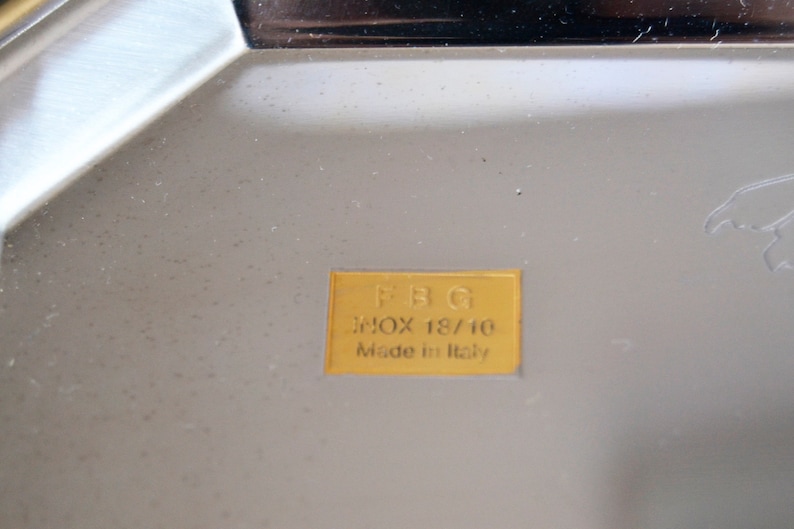 May include: A gold label with the text "FBG" in black lettering, "inox 18/10" in black lettering, and "Made in Italy" in black lettering.