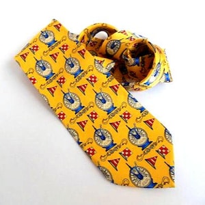 May include: A yellow silk tie with a repeating pattern of blue and white nautical compasses and red and white flags.