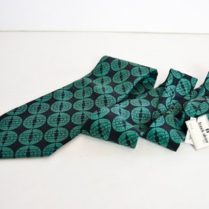 May include: A dark blue tie with a green geometric pattern. The tie has a tag that reads "frank oliver".