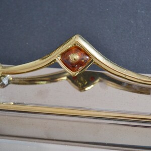 May include: A silver tray with a gold trim and a gold handle. The handle has a square amber-colored stone in the center.