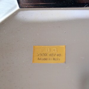 May include: A gold label with the text "FBG" in black lettering, "inox 18/10" in black lettering, and "Made in Italy" in black lettering.