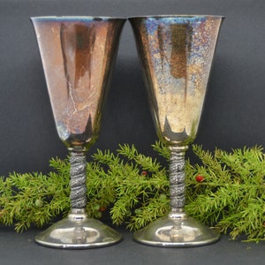 Puede incluir: Dos copas de plata con tallos retorcidos ornamentados. Las copas son de plata pulida y tienen un aspecto vintage.