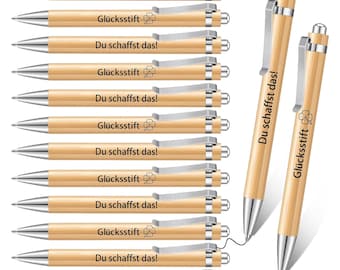 Op de afbeelding: Een set van tien houten pennen met zilveren accenten. Elke pen heeft de tekst "Du schaffst das!" en "Glücksstift" gegraveerd. De pennen zijn in een rij gerangschikt met de puntjes naar de kijker gericht.