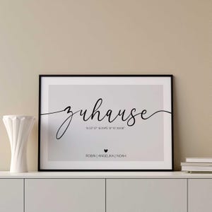 May include: A black and white framed print with the word "Zuhause" in cursive script. The print also includes the coordinates "N 53° 57' 16.704°E 10" 16 20136" and the names "ROBIN | ANGELIKA | NOAH".