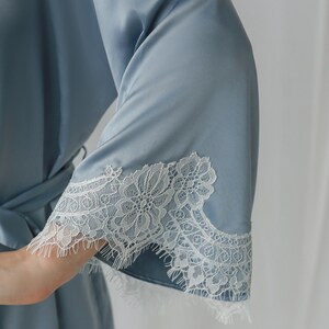 May include: A light blue satin robe with white lace trim around the sleeves.