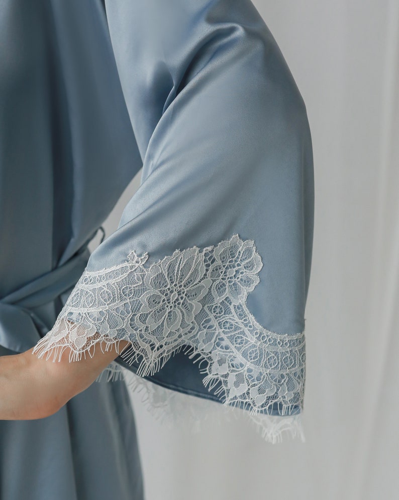 May include: A light blue satin robe with white lace trim around the sleeves.
