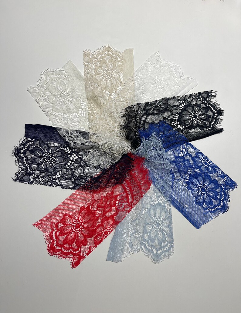 May include: Assortment of lace trims in various colors, including white, beige, black, blue, and red. The lace trims are arranged in a circular pattern, with the edges of each trim overlapping.