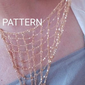Peut inclure: Un collier en métal doré composé de plusieurs chaînes formant un motif en toile. Les chaînes délicates sont reliées entre elles pour créer une structure en grille drapée sur la poitrine. Le mot PATTERN est imprimé en blanc sur l'image.