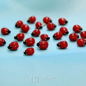May include: A collection of red and black ladybug figurines on a light blue background.