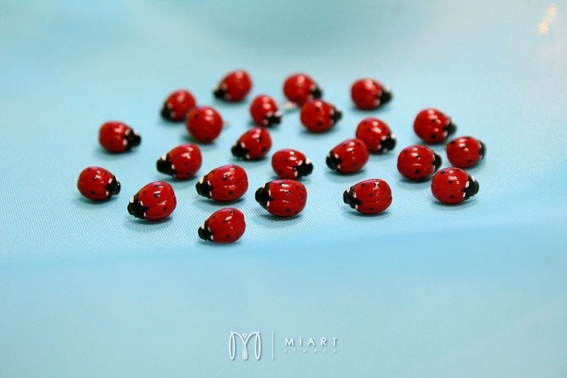 May include: A collection of red and black ladybug figurines on a light blue background.