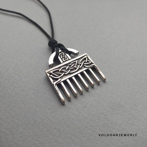 Puede incluir: Collar con colgante de plata con dise&ntilde;o de peine y nudos celtas. El colgante est&aacute; unido a un cord&oacute;n negro.