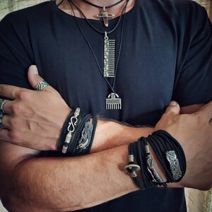 Puede incluir: Una persona lleva una camiseta negra con m&uacute;ltiples pulseras y anillos de plata. Las pulseras son de cuero negro y tienen detalles plateados. Los anillos tambi&eacute;n son de plata y tienen varios dise&ntilde;os.