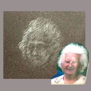 May include: A close-up of a woman with white hair smiling. She is wearing a floral print shirt and has a light blue background behind her.