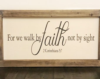 May include: A wooden framed sign with a beige background and black text that reads "For we walk by faith, not by sight" and "2 Corinthians 5:7".