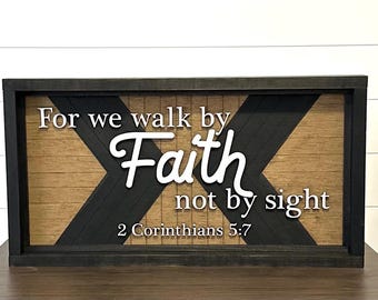 May include: Wooden framed sign with the text "For we walk by Faith not by sight 2 Corinthians 5:7". The background has a chevron design in black and natural wood tones.