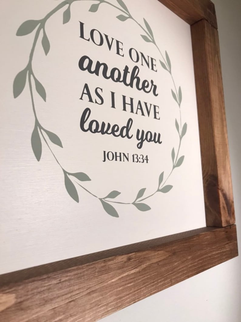 Love One Another Wall decor with wooden stained frame. Bible verse sign white background with Mossy green color wreath.